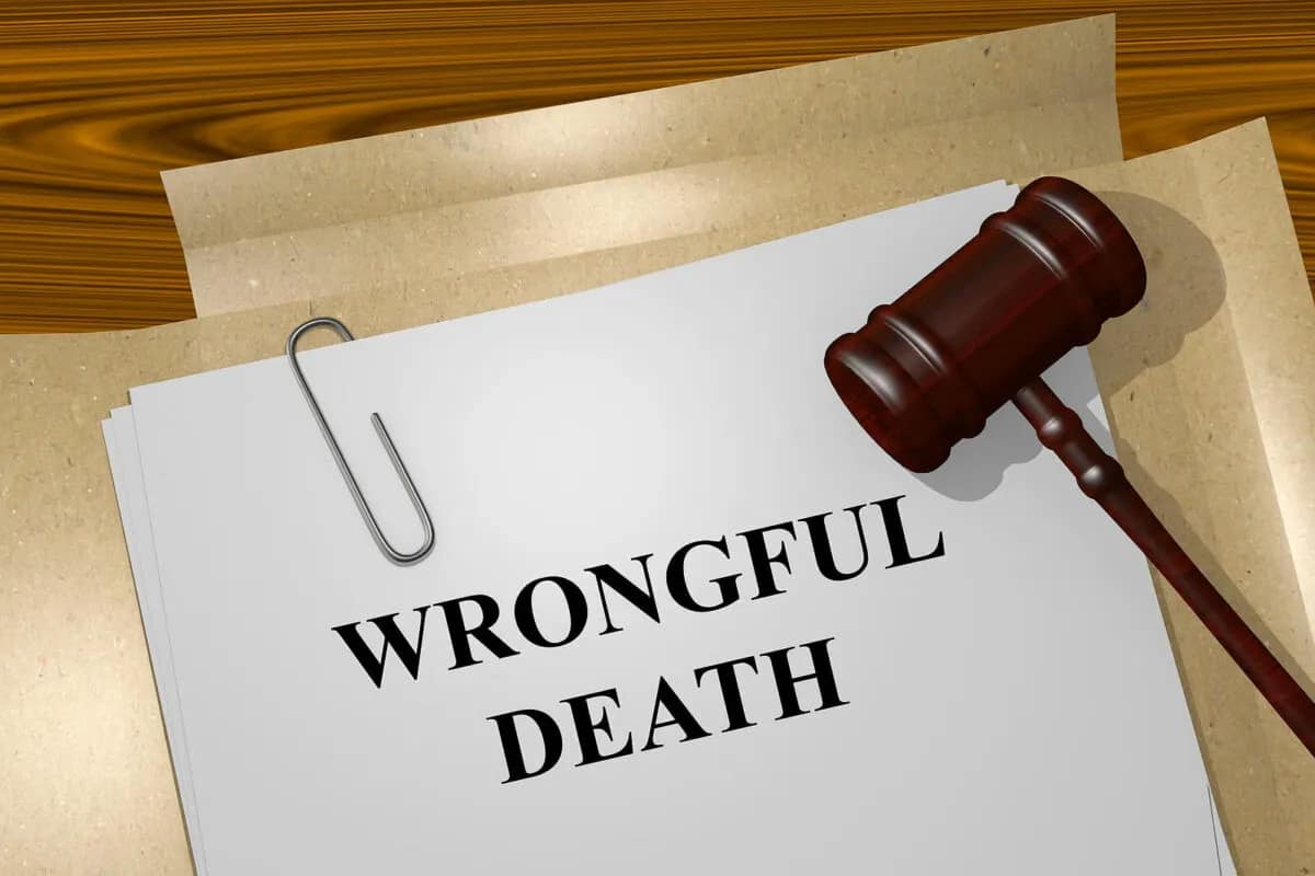A stack of papers labeled "WRONGFUL DEATH" clipped together, with a judge's gavel resting on top, sits on a wooden desk—symbolizing cases handled by a personal injury attorney.