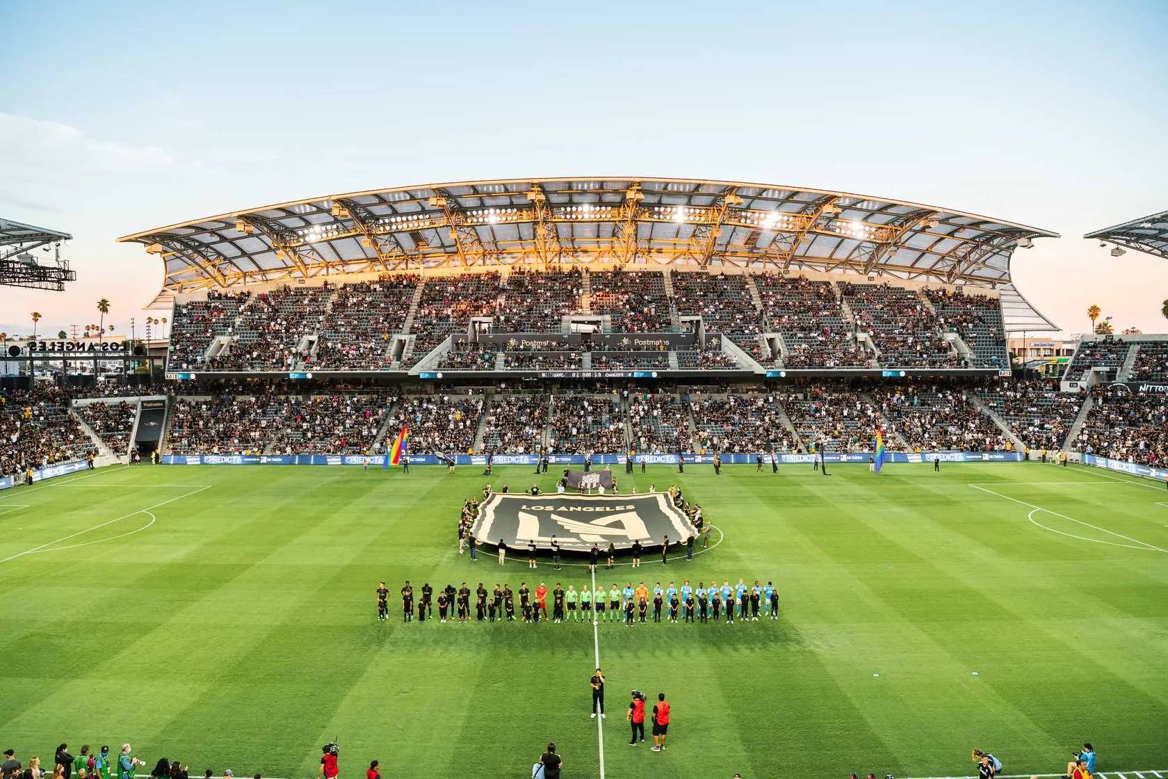LAFC players and match officials line up at midfield inside BMO Stadium
