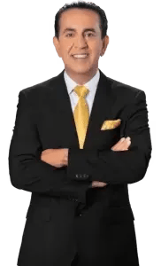 Man in a black suit with a yellow tie and matching pocket square, smiling with arms crossed, standing against a transparent background.