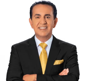 Jacob Emrani de pie con los brazos cruzados, traje negro y corbata amarilla