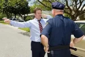 A police officer observes as a man in business attire stands on the street with arms outstretched, seemingly performing a sobriety test under california new traffic laws 2026.