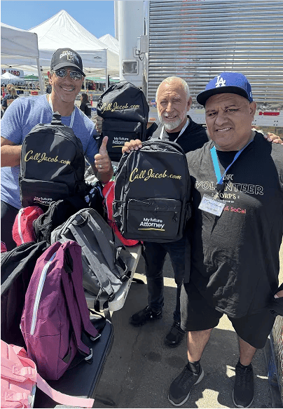 Voluntarios de la comunidad con mochilas de CallJacob.com durante una entrega al aire libre