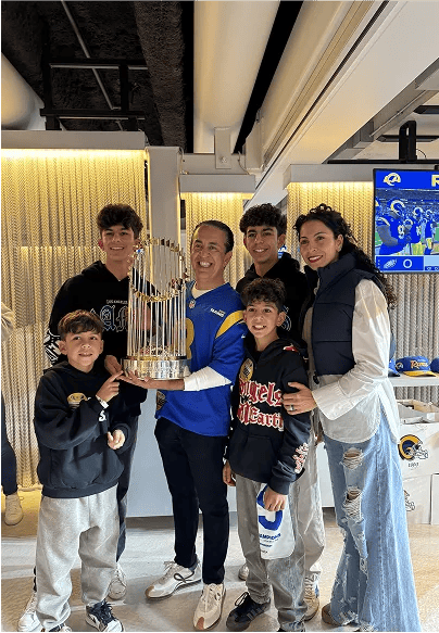 A family celebrating with a Rams trophy at a team event