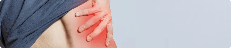A person lifts their shirt to reveal their side, touching an area on their lower back that is highlighted red, indicating pain or discomfort from a possible personal injury.