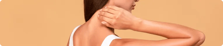 A woman with brown hair, wearing a white tank top, touches the back of her neck—possibly in discomfort—against a beige background. Her face is partially turned away from the camera, conveying the aftermath often seen in car accidents personal injury attorney cases.