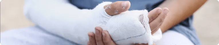 A person gently holding their arm, which is wrapped in a white plaster cast, suggesting a personal injury or broken bone. The softly blurred background adds focus to the tenderness and recovery process.