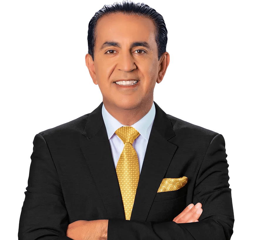 A man with dark hair wearing a black suit, white shirt, and yellow patterned tie stands with arms crossed, smiling confidently at the camera—exuding the professionalism of a Los Angeles Personal Injury Lawyer—against a plain white background.