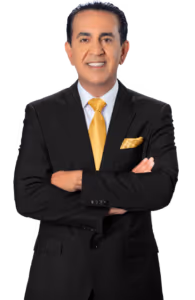 A man in a black suit with a yellow tie and matching pocket square stands with his arms crossed, smiling confidently like a personal injury attorney ready to help after car accidents, against a plain white background.