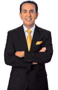 A man in a black suit with a yellow tie and matching pocket square stands with his arms crossed, smiling confidently like a personal injury attorney ready to help after car accidents, against a plain white background.