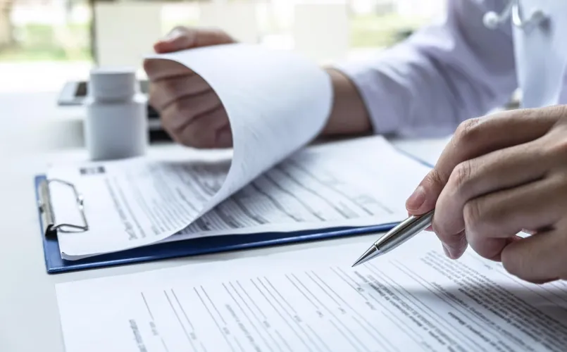 Un profesional médico revisa documentación en un portapapeles.