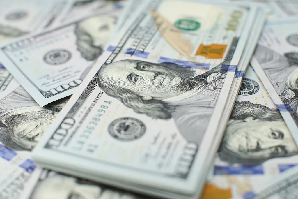 A pile of U.S. one hundred dollar bills scattered and stacked, featuring the portrait of Benjamin Franklin—often seen in settlements handled by experienced personal injury attorneys.