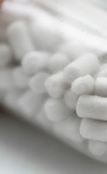 Close-up of a translucent container filled with white cotton swabs, the surface slightly fogged or frosted—much like details can appear blurred after car accidents, making it critical to seek guidance from a personal injury attorney.