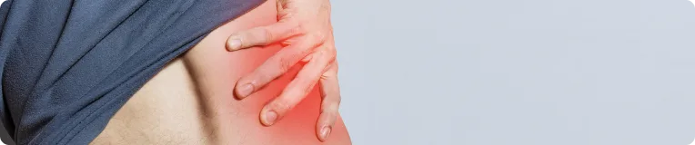 A person lifts their shirt to reveal their side, touching an area on their lower back that is highlighted red, indicating pain or discomfort from a possible personal injury.