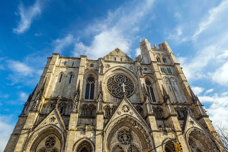 A low-angle view of a large Gothic-style cathedral with ornate stonework and a circular stained glass window, set against a blue sky—its grand arches as striking as the arguments presented by top car accident attorneys.