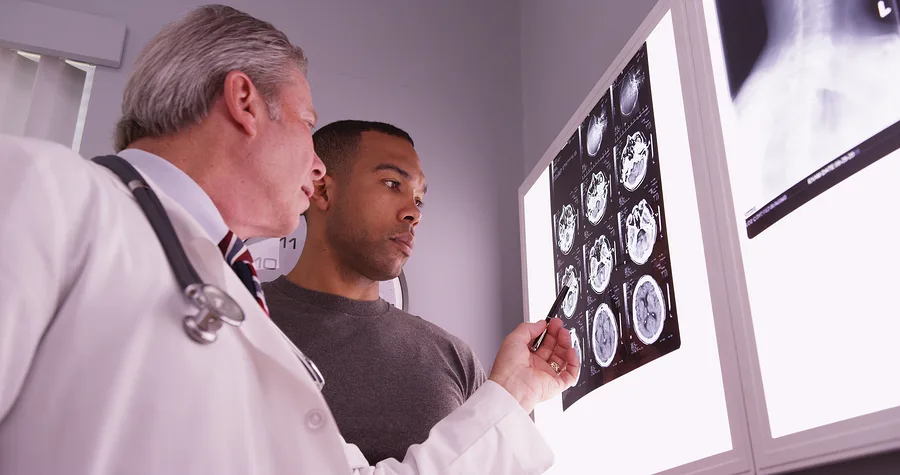 Mid Aged Medical Doctor Reviewing X Ray Of African Patient