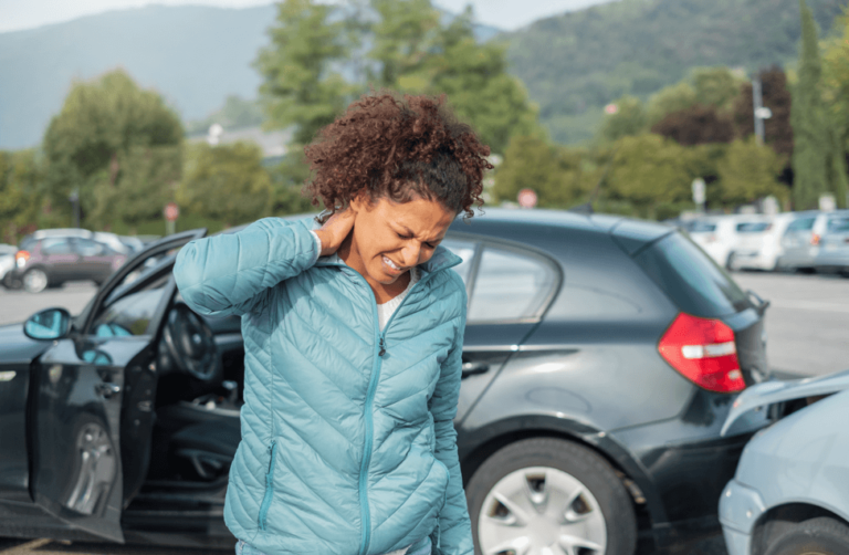 Woman in pain from whiplash at car crash scene