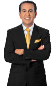 A man in a black suit with a yellow tie and matching pocket square stands with his arms crossed, smiling confidently like a personal injury attorney ready to help after car accidents, against a plain white background.