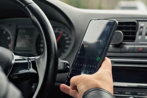 Driver types on smartphone while driving, highlighting the risk and importance of road safety, distraction, and responsible behavior behind the wheel.