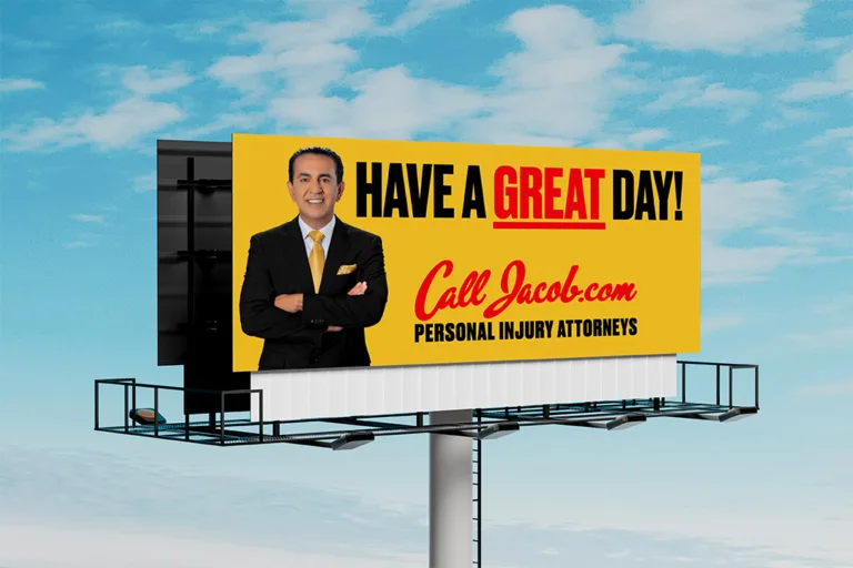 A billboard features a man in a suit with folded arms, and text that says, "HAVE A GREAT DAY! Call Jacob.com PERSONAL INJURY ATTORNEYS" against a yellow background, promoting help for car accidents. The sky is blue with some clouds.