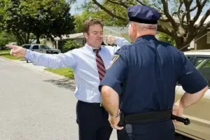 A police officer observes as a man in business attire stands on the street with arms outstretched, seemingly performing a sobriety test under california new traffic laws 2026.