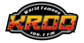 Logo for KROQ 106.7 FM with the words "World Famous" above large orange and yellow "KROQ" lettering, featuring a city skyline and star details inside the letters.