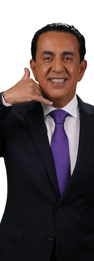 A man in a suit and purple tie smiles while holding his hand to his face in a “call me” gesture, embodying el mero mero confidence against a plain white background.