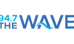 Logo for 94.7 The Wave radio station. The text is mostly blue with "94.7" in light blue and "THE WAVE" in bold blue letters, with a wave integrated into the "A" in "WAVE.