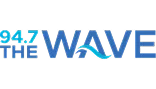 Logo for 94.7 The Wave radio station. The text is mostly blue with "94.7" in light blue and "THE WAVE" in bold blue letters, with a wave integrated into the "A" in "WAVE.