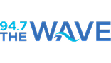 Logo for 94.7 The Wave radio station. The text is mostly blue with "94.7" in light blue and "THE WAVE" in bold blue letters, with a wave integrated into the "A" in "WAVE.
